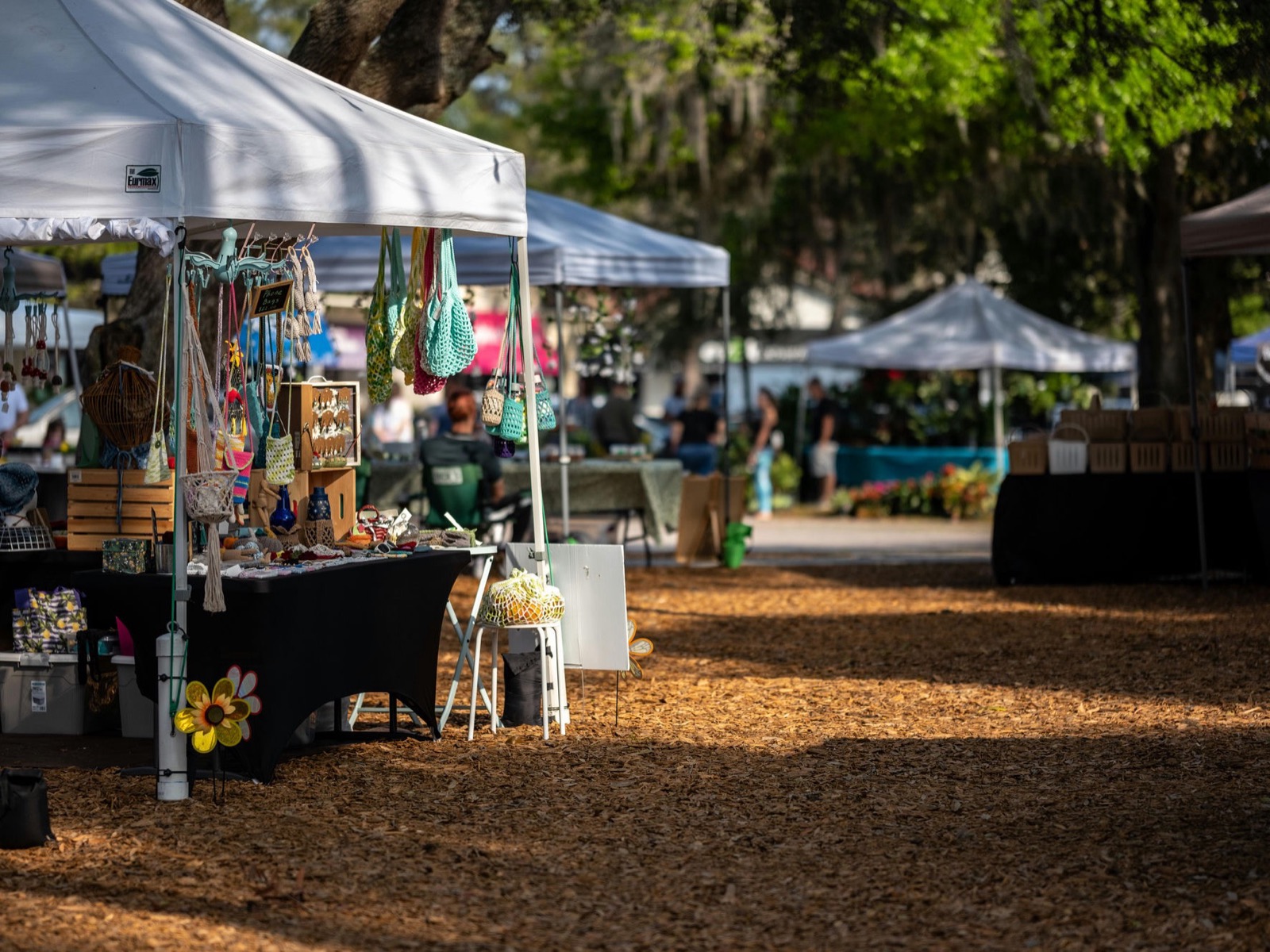 Outdoor vendor market with white tents and handcrafted goods on display